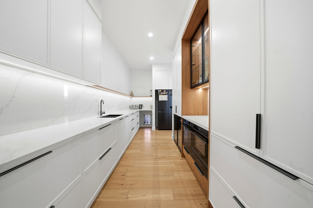 Scullery with white cabinetry and marble benchtop