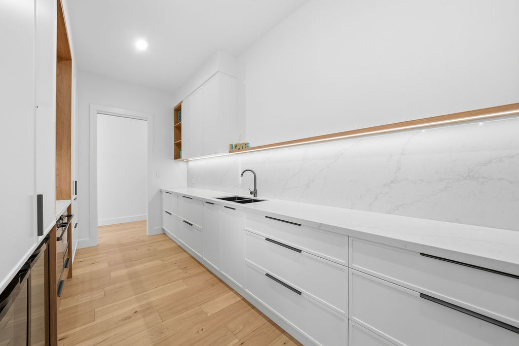 Butler's pantry with marble splashback and lighting beneath the cabinets