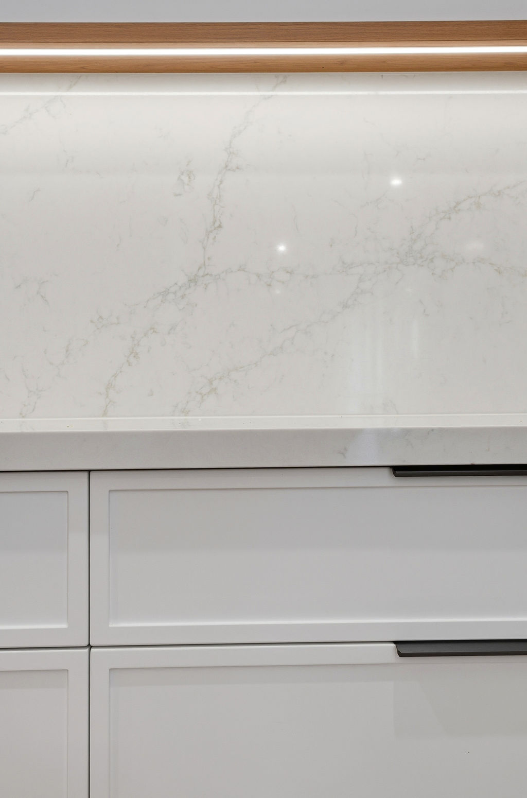 Marble splashback detail with oak ledge lighting