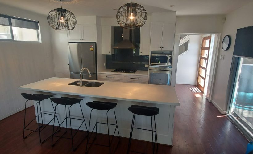 Completed kitchen with island bench, pendant lights and appliances
