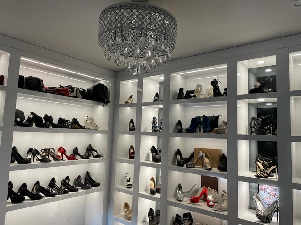 Illuminated walk in shoe robe with floor to ceiling display shelving